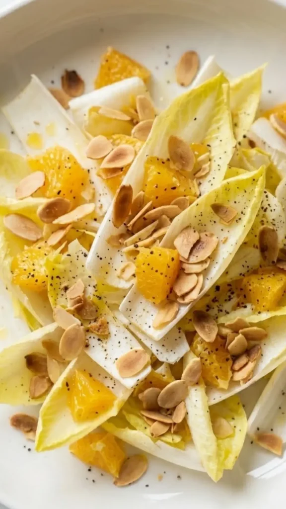 Nahaufnahme von Chicoreesalat mit Orangen — kross geröstete Mandelblättchen auf feinen Salatblättern